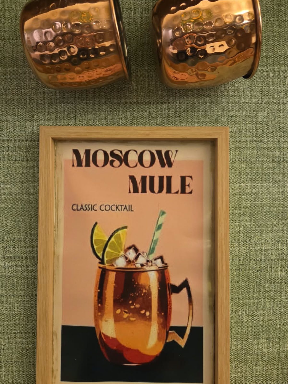 Canecas de cobre e o quadro do Moscow Mule, na parede do Forneatto